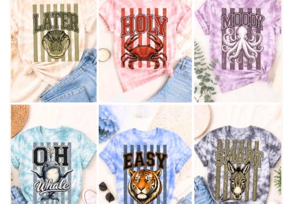 May include: A collection of six tie-dye t-shirts featuring animal graphics and text. The shirts display an alligator with the word LATER, a crab with HOLY, an octopus with MOODY, a whale with OH WHALE, a tiger with EASY, and a donkey with SMART.